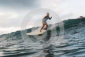 Young woman in bright bikini surfing on a board in ocean