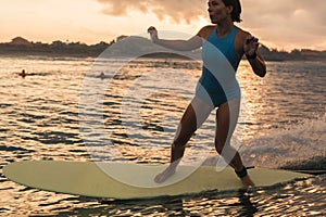 Young woman in bright bikini surfing on a board in ocean