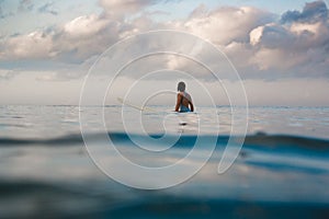 Young woman in bright bikini surfing on a board in ocean