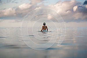 Young woman in bright bikini surfing on a board in ocean