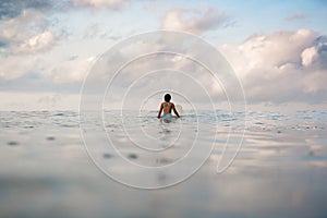 Young woman in bright bikini surfing on a board in ocean