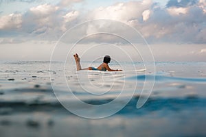 Young woman in bright bikini surfing on a board in ocean
