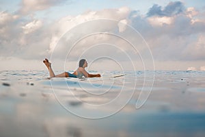 Young woman in bright bikini surfing on a board in ocean