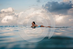 Young woman in bright bikini surfing on a board in ocean