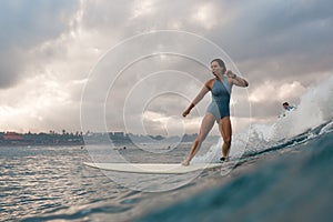 Young woman in bright bikini surfing on a board in ocean