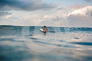 Young woman in bright bikini surfing on a board in ocean