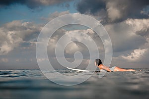 Young woman in bright bikini surfing on a board in ocean