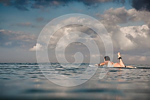 Young woman in bright bikini surfing on a board in ocean