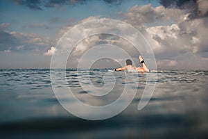 Young woman in bright bikini surfing on a board in ocean