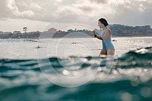 Young woman in bright bikini surfing on a board in ocean