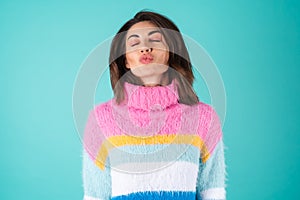 A young woman in a bright multi-colored sweater on a blue background