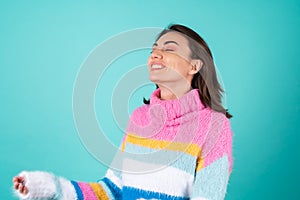 Young woman in a bright multicolored sweater on a blue background