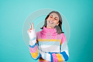 Young woman in a bright multicolored sweater on a blue background