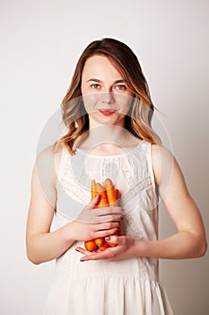 Young woman in a bright room holding a carrot