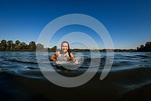 Young woman with brown hair floats on the river on wakesurf board photo