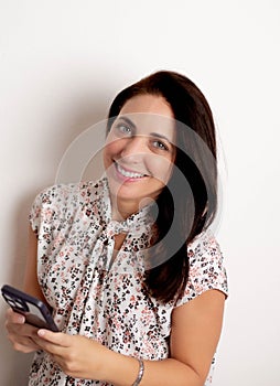 a young woman with brown hair is smiling and holding her phone
