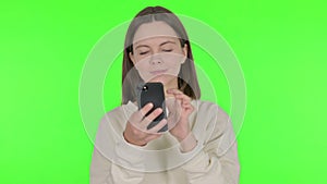 Young Woman Browsing Smartphone on Green Background