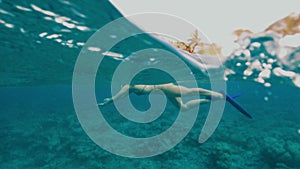 Young woman with brunette hair swims in azure ocean water