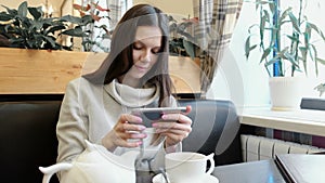 Young woman brunette pictures of teapot and Cup in a cafe on her cell phone.