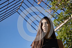 Young woman, brunette, slender and dressed in black, walking, concentrated and thoughtful receiving the sun's rays.