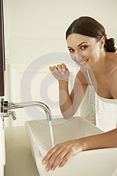 Young Woman Brushing Teeth In Bathroom