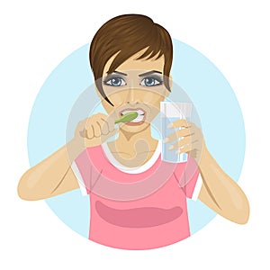 Young woman brushing teeth and holding glass of water