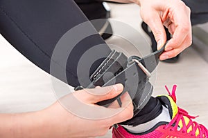 Young woman buckling a leather strap to her ankle