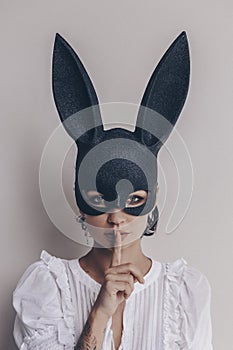 Young woman in bunny mask showing quiet sign