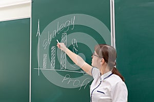 young woman business coach in a white blouse and glasses shows with her hand a diagram of building a business on a graph