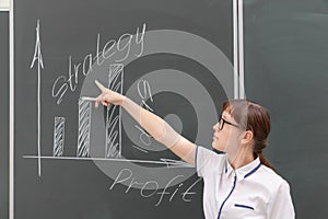 young woman business coach in a white blouse and glasses shows with her hand a diagram of building a business on a graph. office