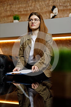A young woman in a business jacket is waiting for an interview for a new job at the reception, an applicant for a vacancy