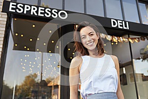 Young woman business owner standing outside cafe shopfront