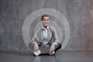 Young woman in business suit sitting in Lotus pose, restore energy, meditate.