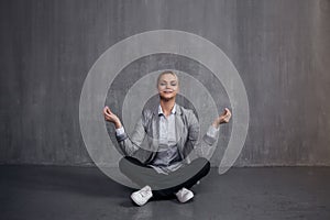Young woman in business suit sitting in Lotus pose, restore energy, meditate. Health and work