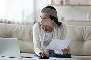 Young woman busy managing household budget using laptop