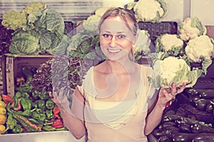 Young woman buying cabbage at market