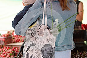 Young woman buying vegetables on stall at the local farmer`s market