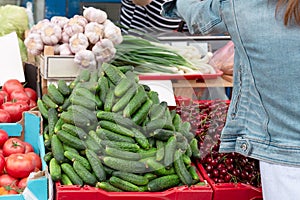 Young woman buying vegetables on stall at the local farmer`s market