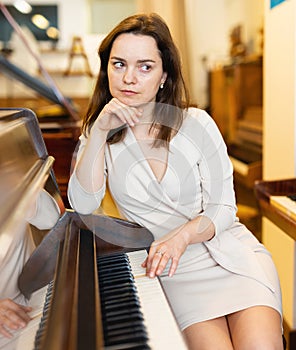 Young woman buys pianoforte in a music store photo