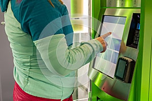 A young woman buys a public transport ticket in a vending machine, urban and agglomeration transport photo
