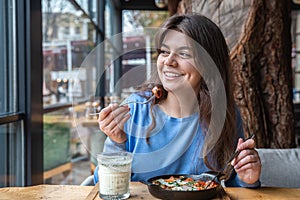 A young woman in a cafe dines on traditional shakshuka and ayran.