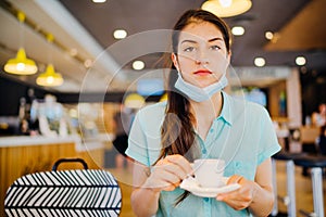 Young woman in cafe public place wearing the protective face mask wrong way.Improper mask wearing.Annoyed person by the