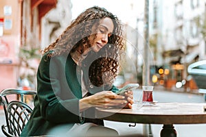 Young woman in a cafe reading a message from her mobile phone