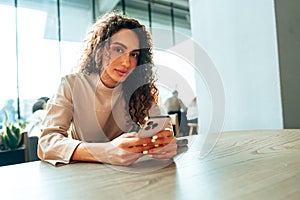 Young woman in a cafe reading a message from her mobile phone