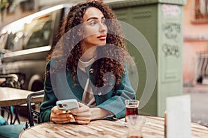 Young woman in a cafe reading a message from her mobile phone