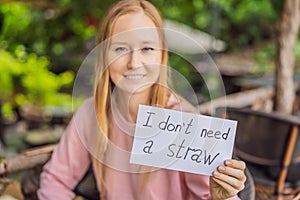 Young woman in a cafe shows a sign - I don`t need a straw. No plastic. Global environmental protection issue