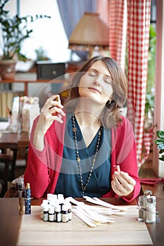 Young woman in cafe with tea set smells perfumes with blotter close up photo