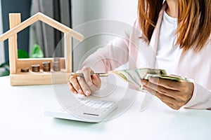 Young woman calculating home expenses with stack of coins, Saving money for property investment concept