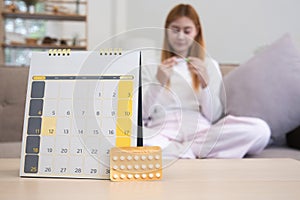 A young woman with a calendar and birth control pills reads instructions on how to use them correctly.