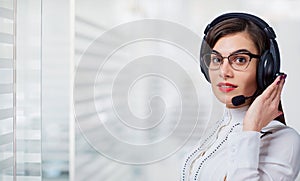 Young woman call center operator in headset on office background